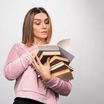girl pink sweatshirt holding stock books opening one top reading it 114579 27065