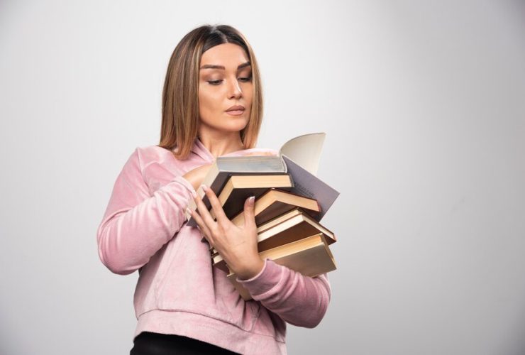 girl pink sweatshirt holding stock books opening one top reading it 114579 27065