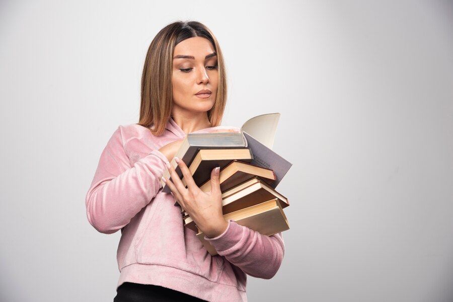 girl pink sweatshirt holding stock books opening one top reading it 114579 27065